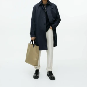 Knälång rock från Arket  - En carcoat tillverkad i en twillkvalitet av bomull och nylon som ger rocken vattenavvisande egenskaper. Den är är helfodrad, knälång och har stilren, dold knäppning framtill. Vid kragen sitter en avtagbar stormflik som kan fästas på insidan av knäppningen