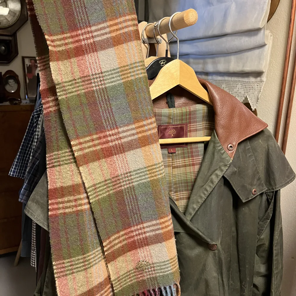 INTESSEKOLL på denna otroliga Fodrad oljerock från Mulburry med detaljer i läder från 1971!😻 Två fickor framtill. Invändigt delvis fodrar i rutig textil. Finns en matchande scarf till som man även kan köpa separat om man vill 😁🤩. Jackor.