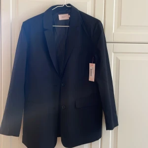 Helt ny kavaj/blazer från Nelly  - Jag säljer en helt oanvänd svart, oversized kavaj/blazer i storlek 34 från Nelly. Oanvänd och lappen sitter kvar. Nypris 700kr, mitt pris 300kr.