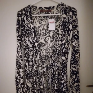 NY oanvänd svart - vit tunika/kimono. Indiska. Storlek: SMALL/36. Viskos. - Helt ny och oanvänd svart vit mönstrad tunika/kimono i omlott-modell med knytband i midjan. Storlek: SMALL/36. Material: Mjuk, bekväm viskos. Lappar/tags sitter kvar sedan inköpet. Helt felfri, den hänger lite snett på galgen på fotona men är normal irl.