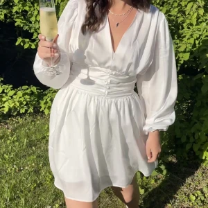 Vit klänning - Säljer min fina studentklänning. Använd 1 gång 2021. Skulle beskriva materialet som en satin-imitation. Klänningen har en dragkedja på sidan för att få korsetteffekten✨