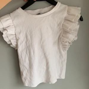 Zara vit topp - Ett linne med volanger,vit och i bra skick, inte änvänd så mycket. Den är i storlek s från zara.