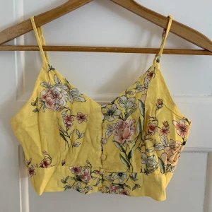 Gul mönstrad topp - Säljer denna fina gula topp i storlek m, passar även någon med storlek s. Knappen längst ner är lite trasig, men den går att stänga.