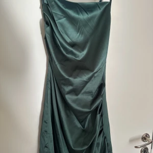Mörkgrön klänning - En mörkgrön klänning från shein. Lårkort, endast använd 1 gång. Banden är som ett kryss i bak. Veckad sydd vid ena sidan på bysten och nere på höften