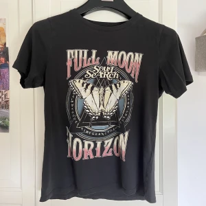 Tshirt med tryck - Snygg svart T-shirt med tryck från Gina. Köpt för många år sedan men sparsamt använd. Storlek M men skulle absolut säga att den sitter lika snyggt på en XS/S. Säljer då jag inte använder den längre.