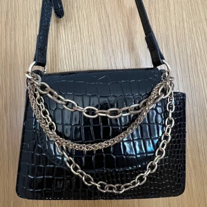Svart Väska - Svart väska med kedje detaljer från SHEIN. Denna väska passar perfekt till alla tillfällen och outfits! Helt okej skick utom lite missfärgning på kedjorna som jag visar på sista bilden. Den har två fack och allt man behöver får plats 💕
