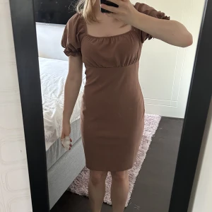 Klänning - Otroligt fin brun klänning från bikbok! Tyvärr är den lite för stor för mig. Använt en gång tidigare och är felfri! Går även att ha ärmarna off shoulder! Passar S men även M!