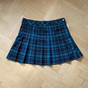 Rutig kjol - Aldrig använd.  42cm bred midja. Plisserad grön/svart rutig kjol.