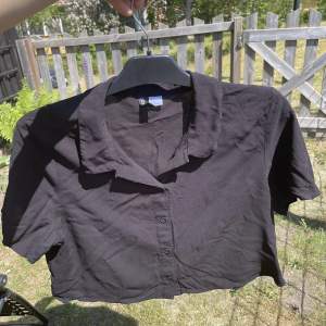 En svart magtröjad och kortärmad skjorta. Den har ett sorts blus material. Den har använts en gång och ser ut som ny. 