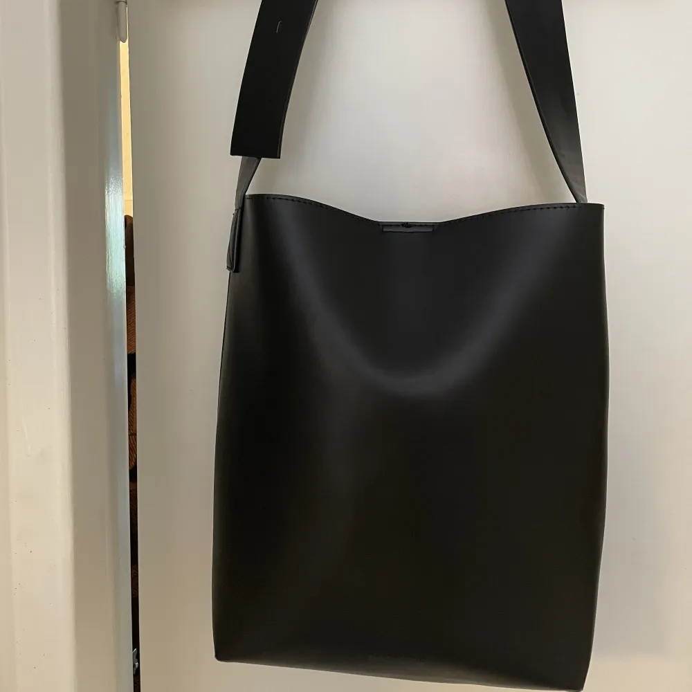 Shopperväska i läderimitation i modellen Celeste från Carin Wester. Använd fåtal gånger.  Justerbar axelrem med stort spänne Inuti finns 1 innerficka och 1 kortfack • Mått:  Bredd 36 cm Höjd 34 cm Djup 13 cm . Väskor.