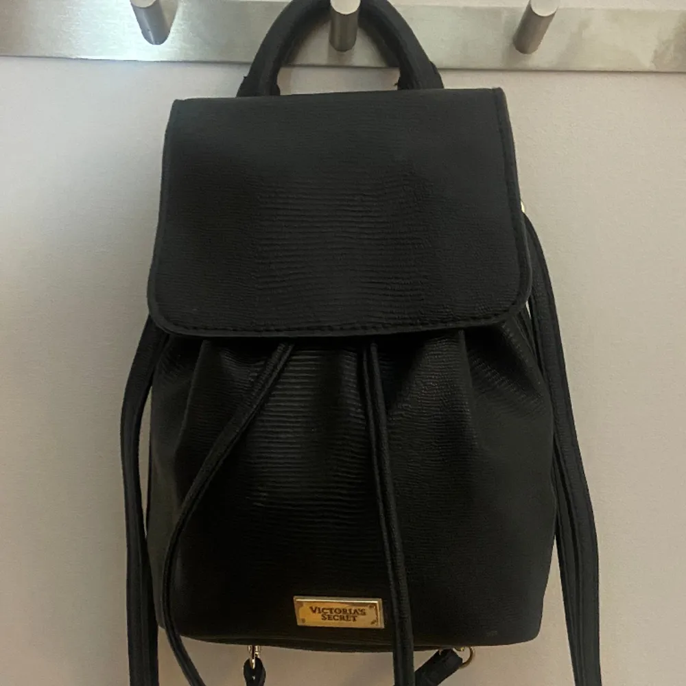 Säljer min vintage victorias secret Victoria Mini  Black Faux Leather Pull Drawstring backpack !! Super gullig mini ryggsäck som är rymlig, och aldrig använd💓 kan skicka fler bilder vid behov!! (Vid bild 3 har jag den över endast en axel). Väskor.