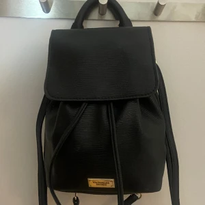Victorias secret mini backpack - Säljer min vintage victorias secret Victoria Mini  Black Faux Leather Pull Drawstring backpack !! Super gullig mini ryggsäck som är rymlig, och aldrig använd💓 kan skicka fler bilder vid behov!! (Vid bild 3 har jag den över endast en axel)