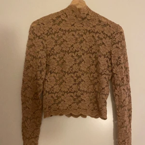 Beige spetströja - Säljer en jättefin spetströja i beige. Toppen har även en högre nacke och är på gränsen till croppad.