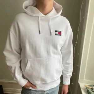 Tommy hoodie storlek L - En vit hoodie från Tommy Jeans i storlek Large, två små fläckar vid fickan som ni ser på sista bilden😈