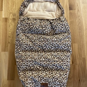 Åkpåse vagn från Kuling - Kuling åkpåse leopardfärgad. Nyskick, lägre pris pga av att pälsen saknas. Totallängd cirka 95 cm. Nypris 1000:-   500:-