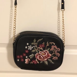 Väska - Superfin väska med broderade blommor framtill, stängs med dragkedja. Använt skick.