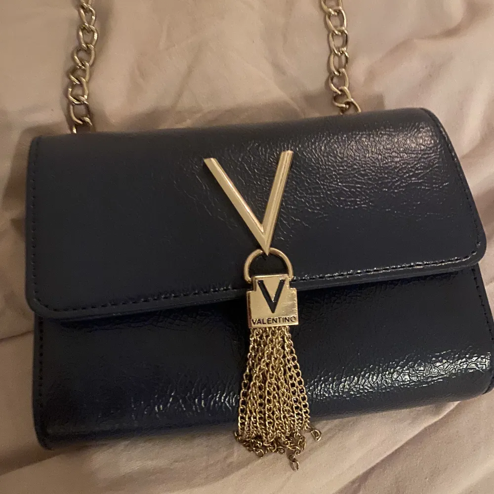 Mörkblå valentinoväska med guldiga band samt detaljer🫶🏻säljer pga att jag använder andra väskor mera. Inga defekter. Nypris 899. Väskor.