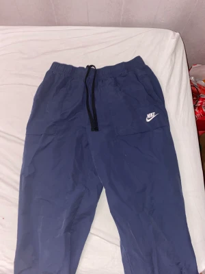 Nike byxor  - Säljer ett par blå Nike byxor för de är inte min stil, bra sick och har typ lite vintage stil och sitter ganska slim