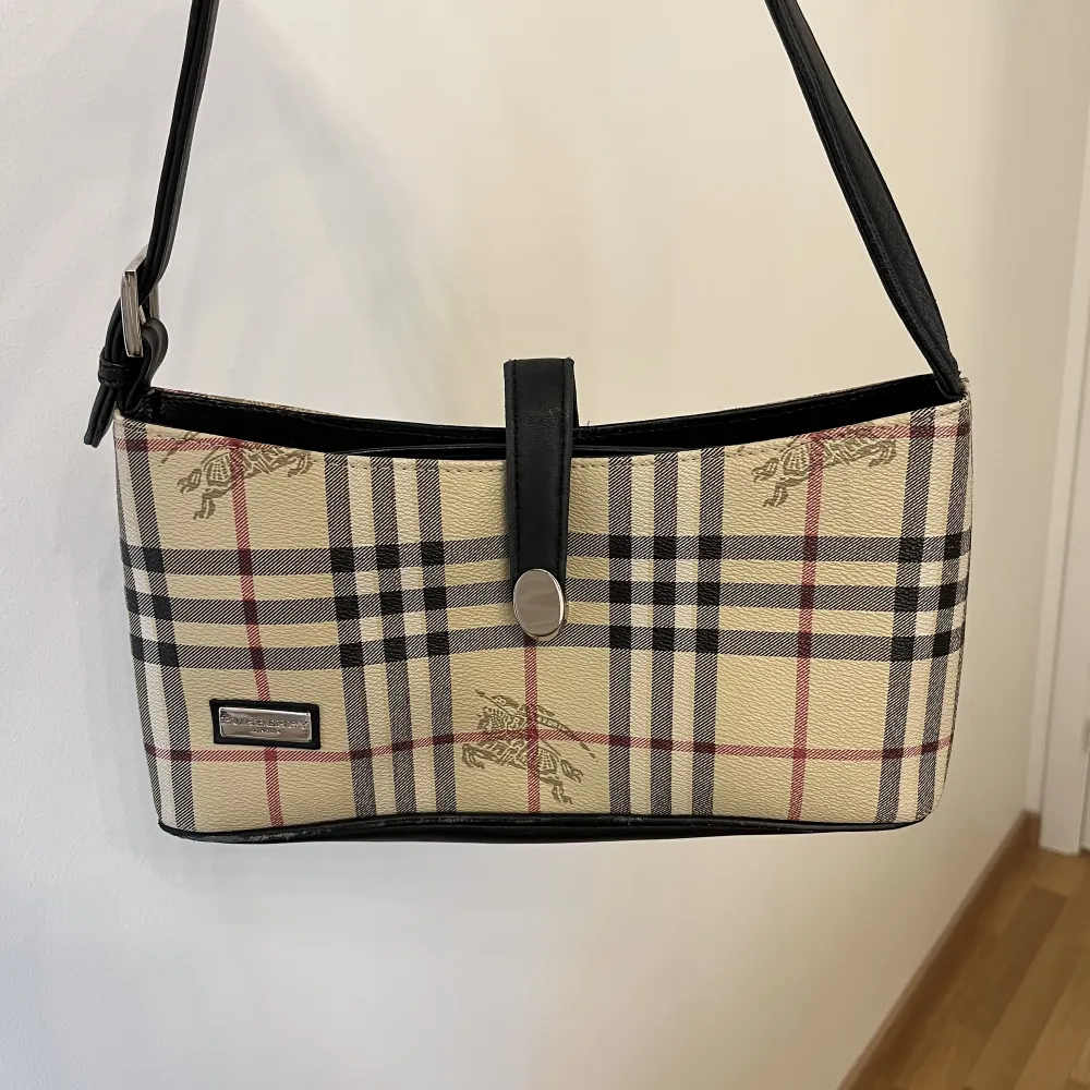 En kopia av en Burberry väska i väldigt bra material. Bra skick och inga defekter. Väskan har två innerfack och är rätt så rymlig. Längd: 29 cm, Höjd: 16 cm. Väskor.