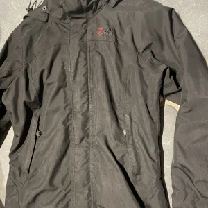 Fjällräven jacka  - En fjällräven jacka (XS) söker nytt hem då jag själv har för många jackor av samma stil och syfte.   Lätt lite längre fjällräven jacka med  rymliga fickor framtill och längs insidan av jackan samt med huva. Utan hål/ dylikt som påverkan funktion.  