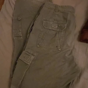 Cargo byxor - Skit snygga gröna cargos, Sytt de vid midjan så de passar mig bättre men går att sprätta upp. Några defekter finns längst vid benen är de slits men inget som syns, och en fläck på baksidan inte sp synligt