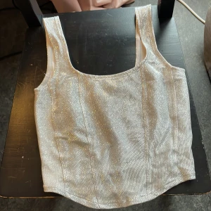Glittrig festtopp - Perfekt festtopp med corset liknande stil till nyår! Använd en gång och är i bra skick. Skriv om du har fler frågor!