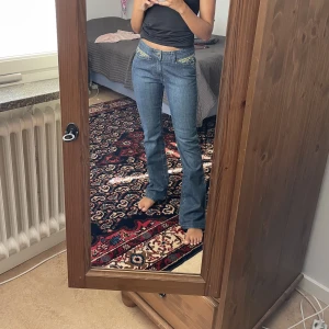 Bootcut jeans med brodyr - Säljer ett par jättefina bootcut jeans i storlek XS eller midjemått 24-25 som inte sitter perfekt på mig. Uppsydda så att de passar någon som är ca 160cm. Obs ljusare i verkligheten som första bilden 