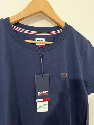 En marinblå t-shirt - En marinblå t-shirt från Tommy. Den är helt ny. Storlek XL men den är lite i storlek så den passar de som har storlek L/M. Köparen står för frakt