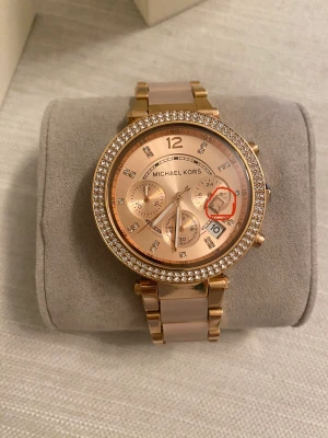Michael kors - Michael kors klocka i rosé färg, säljer billigt för att jag vill bli av med den, köpt för några år sedan men knappt använd.En liten del i klockan har lossnat men finns kvar i uret, går säkert att fixa.  Finns länkar så man kan juster storleken,batteribyte