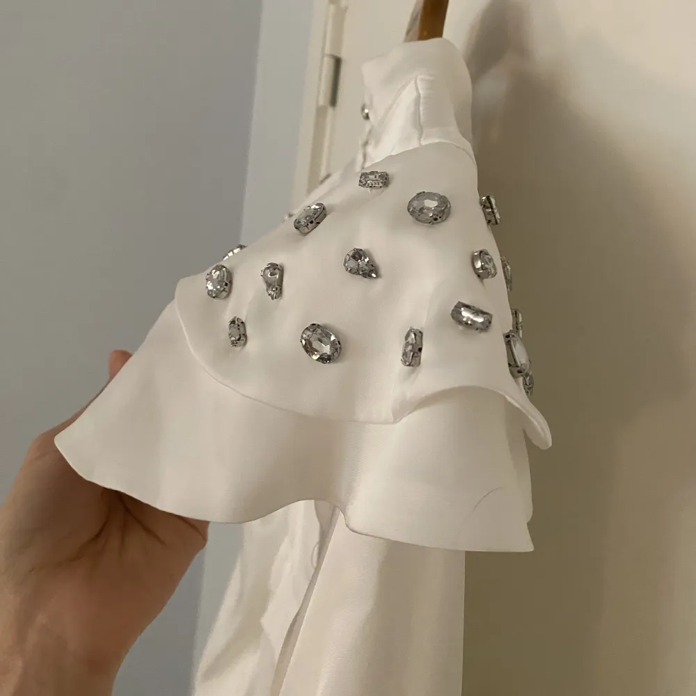Aldrig använd med lappen på. Vit klänning med ballongärmar och stenar på axlarna. Den är i storlek M och framhäver midjan på ett fint sätt. Skulle använda den som min bröllopsklänning. . Klänningar.