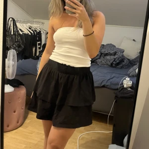 Volangkjol - En svart kort volangkjol från Gina. Kan användas både högmidjade och lågmidjat. Fint skick 