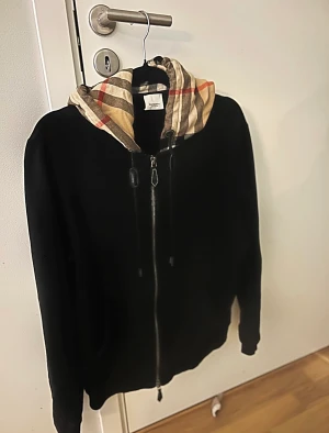 Burberry kofta & byxor - Burberry Byxor  Material kalvskinn 100%, bomull 76%, polyester 24% maskintvätt Burberry Kofta Svart/flerfärgad, bomull, rutigt mönster, huva med dragsko, dragkedja i fram, långa ärmar, två sidofickor Inköpt från NK tidigare detta året,  Nypris: 18.000