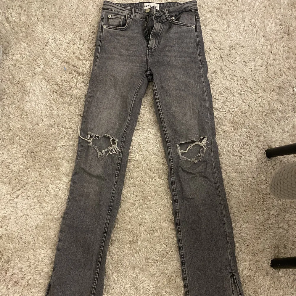 Gråa Zara jeans med slits längst ner och medelhög midja. . Jeans & Byxor.