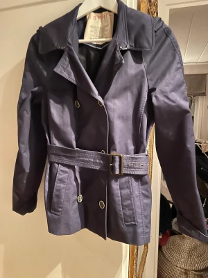 Trenchcoat från Esprit - Fint skick i storlek 36. Jackan har en kort passform och är dubbelknäppt med midjebälte. 