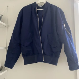 Marinblå bomberjacka, Filippa K - En marinblå bomberjacka från Filippa K. Med två fickor fram och en ficka på ärmen. Guld dragkedja. I väldigt bra skick!