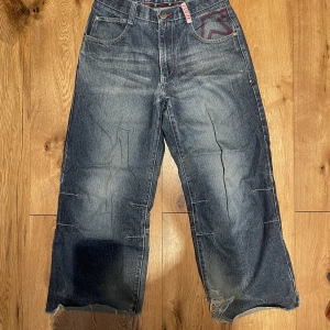 Fugo y2k jeans klippta - Säljer dessa då de inte används längre. Sjukt snygga vida Fugo jeans som är klippta vid anklarna, även skadade där så jag har satt fast med sälerhetsnålar. Lite korta på mig men sitter perfekt och assnyggt om jag saggar (är 175cm). Pm för fler bilder!
