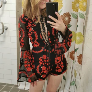 Blommig Playsuit Nasty Gal Stl S - Jättevacker playsuit (byxdress) från Nasty Gal med fina detaljer och djup snörning över brösten. Stl S och dragkedja i rygg. 