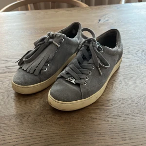 Mocka sneakers Mikael Kors  - Ljusblå mocka sneakers från Mikael kors i fint, men använt skick. Plös med fransar går att plocka bort   Nypris 1499:-