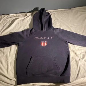 GANT SHIELD HOODIE - Storlek S Skick 8,5/10 Passar ålder runt 12-15 Rekommenderad längd 160-170 Säljs för 100 (kan dock förhandlas) Original pris 900      
