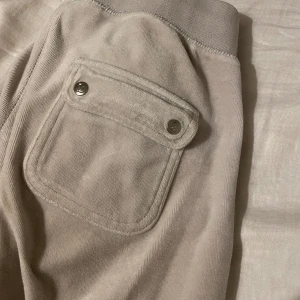 Juicy Couture mjukisbyxor - Gråa fina juicy Coutore byxor, flitigt använda och har lite små fläckar bland annat längst ner då de är relativt långa. Går säkert att tvätta bort med medel men har ej prövat.. Ena knappen på byxan går även ej att knäppa men inget som syns 