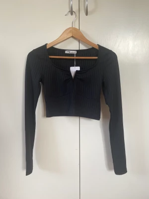 Svart topp - Fin svart cropped topp med långa ärmar från new yorker med detalj på framsidan. Aldrig använd och lappen finns kvar