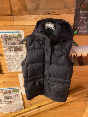 peake performance - peake performance väst med luva som går att ta bort. Färgen är lite mer åt svarta hållet än blå   Vi är en Second hand butik i Knivsta på 600 kvm som säljer möbler, prylar och kläder!  
