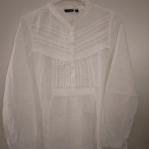 Vit luftig vintage blus med broderier och volanger. Felfri. Bomull. Strlk XS-S. - Vit luftig vintage romantisk blus med broderier och volanger. Sval och jätteskön att ha på sig varmare dagar. Bomull. Strlk XS-S. Använd men ok vintage skick- se bilder. 