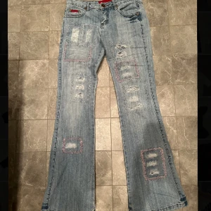 Lågmidjade bootcut jeans - Lågmidjade bootcut jeans med hål. Säljer då de är försmå, inga bilder på!!  Midjemått 76cm innerbenslämgd 82cm