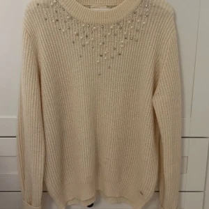 Stickad tröja med detaljer  - Beige/vit stickad tröja.  syns inte på bilden men den är mer vit i verkligheten, jätte fin  Säljer då den är för stor på mig Liten fläck längst ner på tröjan men inget som är jätte synligt