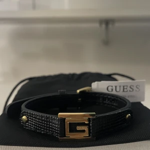GUESS armband  - 🖤GUESS armband i svart läder med guld detaljer! Oanvänt, prislappen sitter kvar. GUESS Smyckespåse tillkommer med armbandet 🖤
