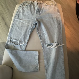 Jeans  - Fina ljusblå jeans med hål i knäna, high  rise. Använd fåtal gånger. Momjeans- breda i längden