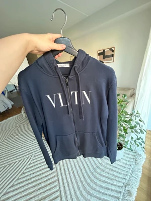 Valentino hoodie - Mörkblå valentino hoddie med dragkedja, i ett jättefint skick. Den är i storlek medium/M, och köptes för 6500kr för ungefär 1 år sedan.