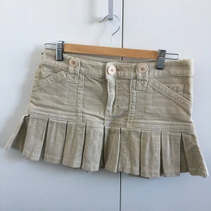 Beige kjol, Calvin Klein Jeans - Min systers lågmidjade kjol från Calvin Klein Jeans, jättefint skick! Lågmidjad och veckad nertill, i manchestertyg. Perfekt till sommaren! Storlek S. Mått, midja: 39 cm, längd fram: 29,7 cm, längd bak: 32,5 cm.