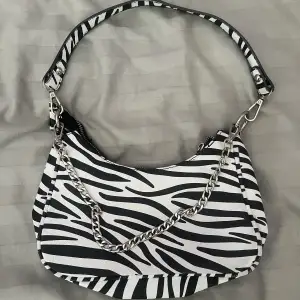 Säljer denna zebramönstrade väska som jag köpte från ett Uf eftersom jag inte fått användning för den på länge! Tillkommer med band och kedja. Sista bilden visar den enda defekten. Pris kan diskuteras💓💗💕